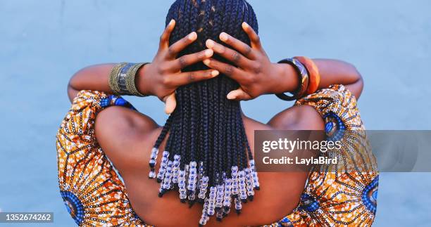 scatto in retrovisione di una giovane donna che indossa abiti tradizionali africani e sente i suoi capelli su uno sfondo blu - african hair foto e immagini stock