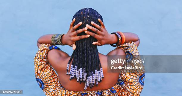 scatto in retrovisione di una giovane donna che indossa abiti tradizionali africani e sente i suoi capelli su uno sfondo blu - bead foto e immagini stock