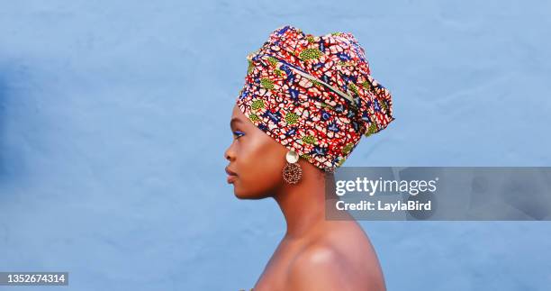 shot of a beautiful young woman wearing traditional african clothing against a blue background - head tie stock pictures, royalty-free photos & images