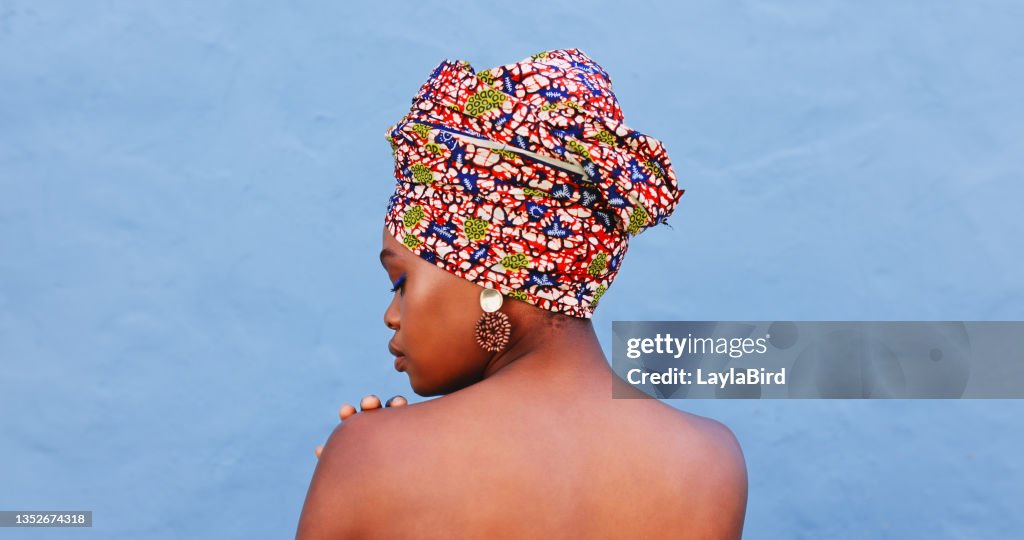 Aufnahme einer schönen jungen Frau in traditioneller afrikanischer Kleidung vor blauem Hintergrund