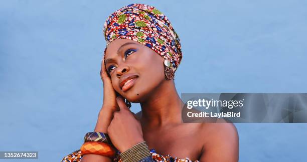 shot of a beautiful young woman wearing traditional african clothing against a blue background - head tie stock pictures, royalty-free photos & images