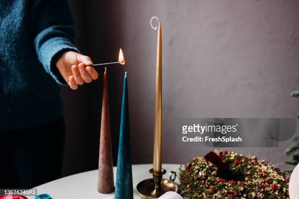 hand einer anonymen frau, die weihnachtskerzen anzündet - blue candle stock-fotos und bilder