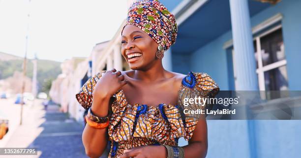 shot of a beautiful young woman wearing traditional african clothing against an urban background - tradição imagens e fotografias de stock