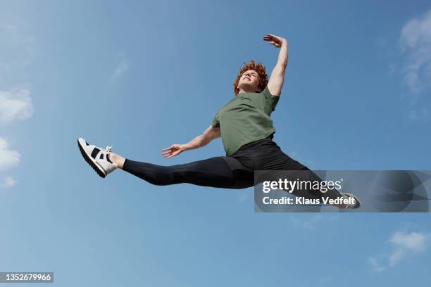 smiling young male dancer performing grand jete - split acrobatiek stockfoto's en -beelden