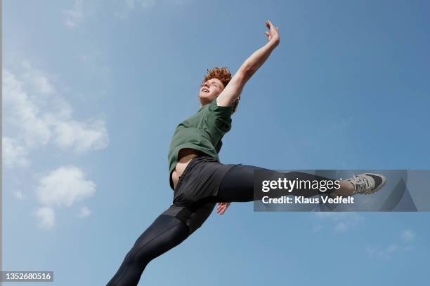 young male ballet dancer practicing on sunny day - mann freudensprung sonne vorderansicht leger stock-fotos und bilder