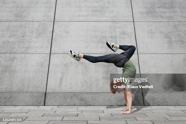 young male dancer balancing on footpath - flexibilität stock-fotos und bilder