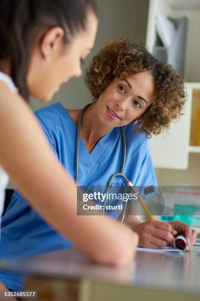 young woman chatting to a triage nurse - medical document stock pictures, royalty-free photos & images