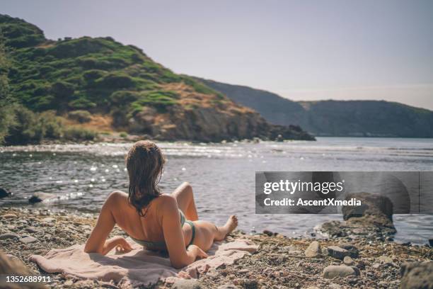 la giovane donna si rilassa sulla spiaggia dopo la nuotata mattutina - riva del lago foto e immagini stock