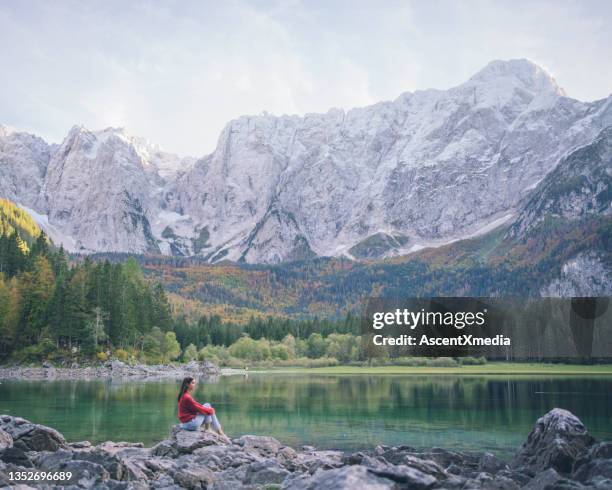 young woman relaxes near alpine lake, in autumn - lakeshore stockfoto's en -beelden