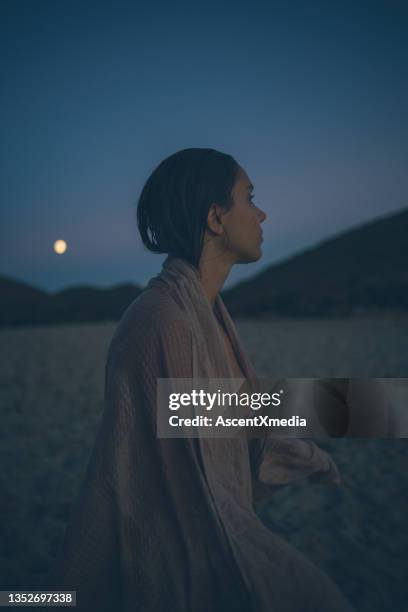 des jeunes femmes enveloppées dans une serviette se détendent sur la plage au crépuscule - pleine lune photos et images de collection