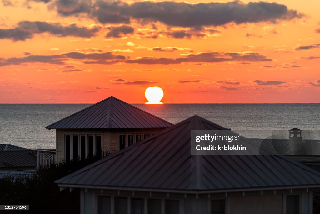 Aerial view on colorful yellow sunset sun omega in horizon with ocean landscape of Gulf of Mexico in Seaside, Florida from rooftop terrace buildings houses home