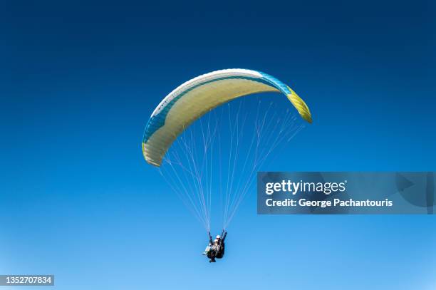 low angle view of a paraglider in the clear blue sky - parachuting stock pictures, royalty-free photos & images