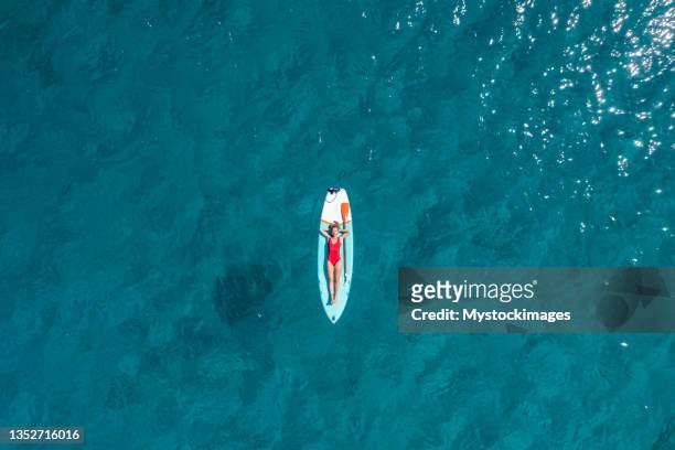 aerial view of woman floating on a stand up paddle - drijven stockfoto's en -beelden