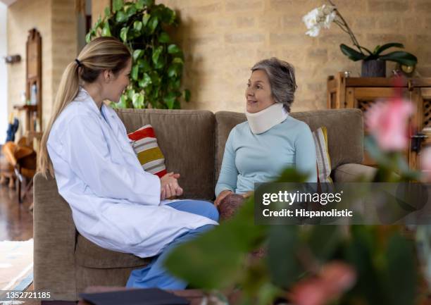 doctor making a house call and talking to a senior patient with a neck injury - cervical collar stock pictures, royalty-free photos & images