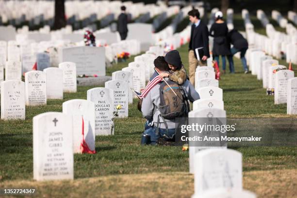 Army veteran Stephen Hedger is hugged by his son Lincoln as he visits the gravesite of U.S. Army Major Paul Douglas Carron at Arlington National...