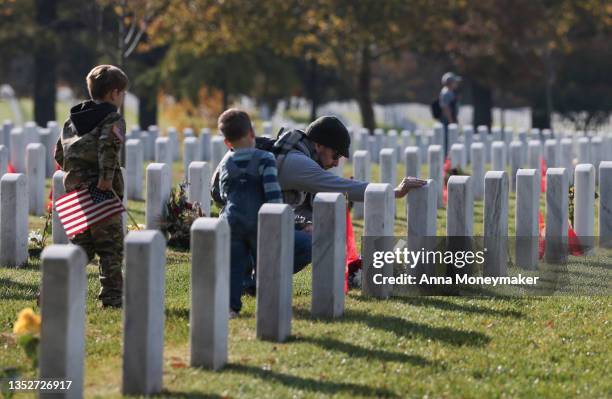 Army veteran Stephen Hedger and his sons visit the gravesite of U.S. Army Major Paul Douglas Carron in Arlington National Cemetery on Veterans Day,...