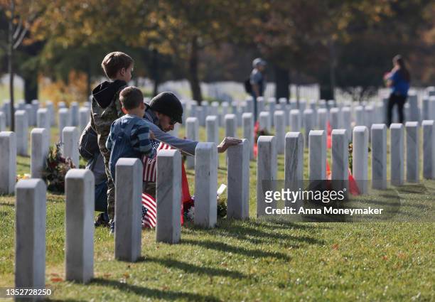 Army veteran Stephen Hedger and his sons visit the gravesite of U.S. Army Major Paul Douglas Carron in Arlington National Cemetery on Veterans Day,...