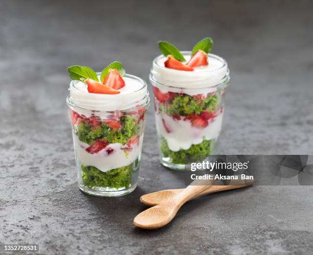 dessert made of layers of spinach biscuit, cottage cheese cream and fresh strawberries, in a glass on a dark gray background - tiramisu stock-fotos und bilder