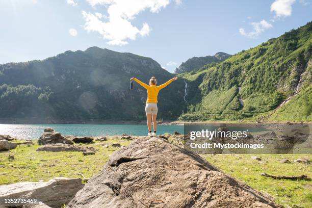 young woman on mountain top arms outstretched - arms outstretched mountain stock pictures, royalty-free photos & images