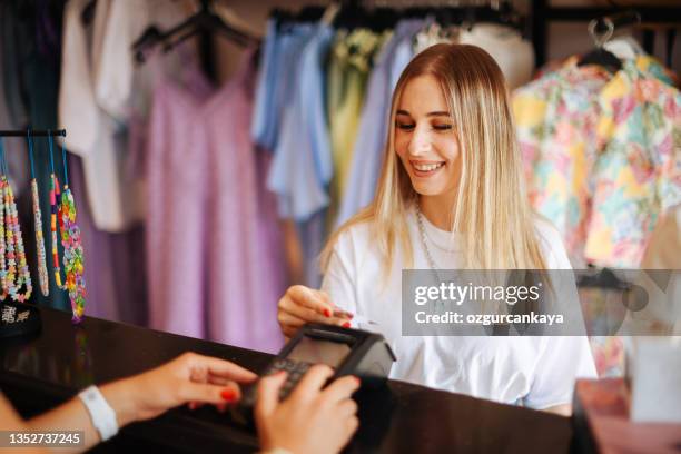 woman purchasing clothes with credit card - smart card stock pictures, royalty-free photos & images