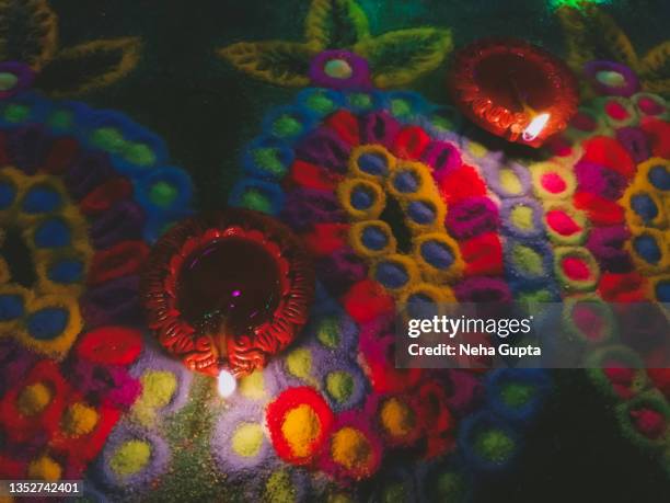 illuminated clay diya, colorful rangoli in the background - diwali, the hindu festival of lights - indian entertainment art and culture fotografías e imágenes de stock