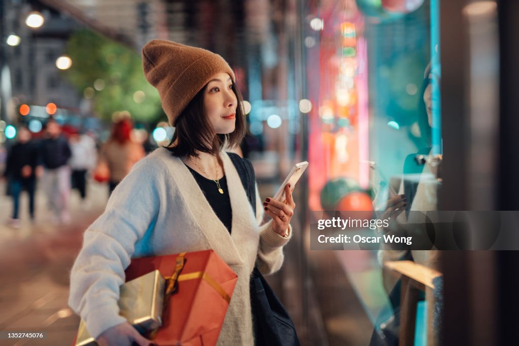 Young woman using smartphone while shopping Christmas gifts