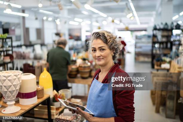 portrait of a saleswoman checking out products at a decoration store - portrait department store stockfoto's en -beelden