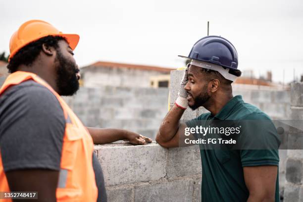 worried coworkers talking in a construction site - wrong job stockfoto's en -beelden