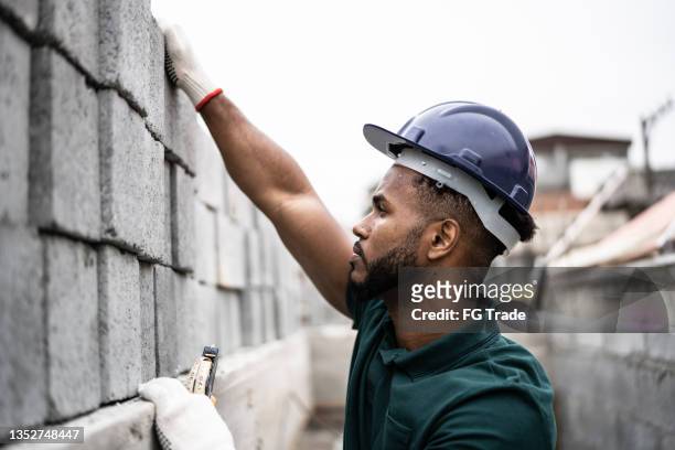 ouvrier de la construction d’un mur de briques - maçon photos et images de collection