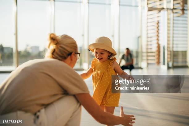 an anonymous mother greeting her daughter and husband at airport - baby gate imagens e fotografias de stock