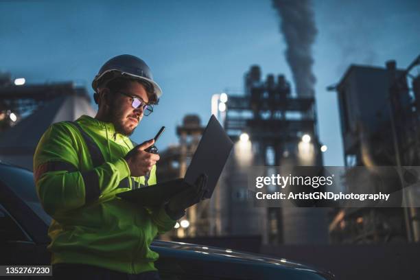 engineer using laptop and walkie talkie during night shift. - nuclear energy worker stock pictures, royalty-free photos & images