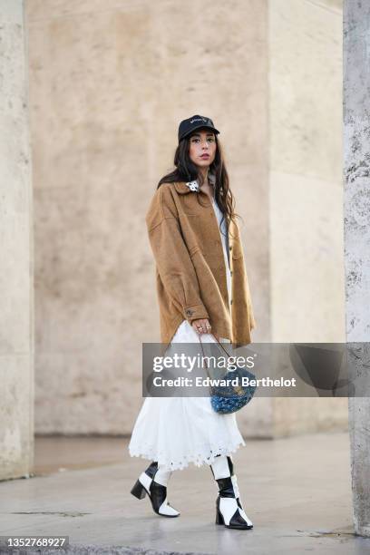 Gabriella Berdugo wears a white gathered and embroidered "boheme" long dress from Magali pascal, a wool mohair camel / brown oversized jacket from...