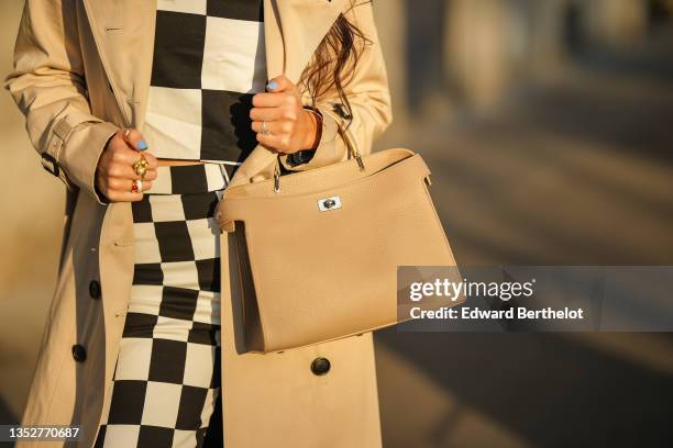 Gabriella Berdugo wears a beige trench long coat from Trench London, a black and white checkered print top from Zara, matching high waist pants from...