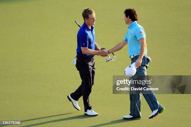 Luke Donald of England shakes hands with his playing partner Rory McIlroy of Northern Ireland at the end of their first round of the Dubai World...