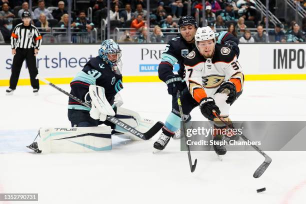 Mason McTavish of the Anaheim Ducks chases a rebound off the pad of Philipp Grubauer while defended by Mark Giordano of the Seattle Krakenduring the...