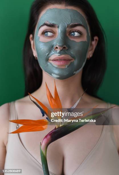 girl with a clay mask on her face and a flower. - build presents sensitive skin imagens e fotografias de stock