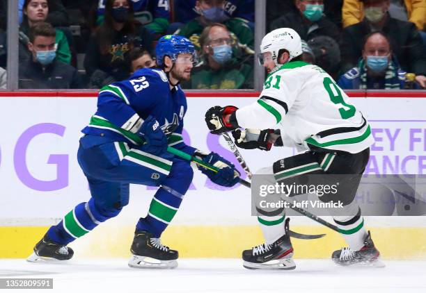 Oliver Ekman-Larsson of the Vancouver Canucks checks Tyler Seguin of the Dallas Stars during their NHL game at Rogers Arena November 7, 2021 in...