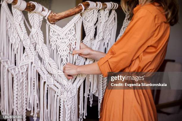 young woman making a macrame work inside her house - macrame stock-fotos und bilder