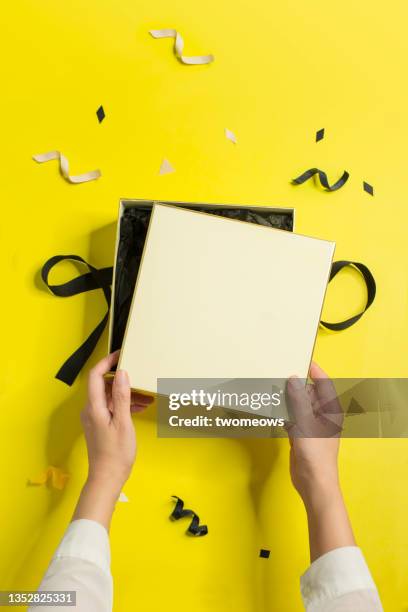 yellow and black coloured gift boxes with  hand still life. - hand with gift stock pictures, royalty-free photos & images