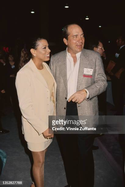 American actress Rolonda Watts, wearing a cream suit, and American former professional baseball player Johnny Bench, in a grey jacket, white shirt...