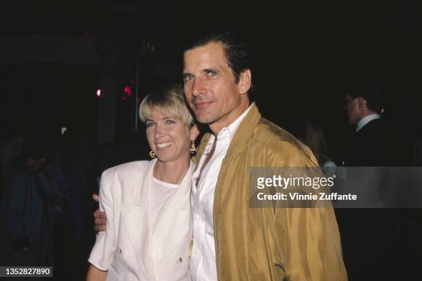 American actress Toni Hudson, wearing a white jacket over a white top, and her husband, American actor Dirk Benedict, wearing a tan jacket over a...