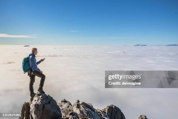 hiker checking smartphone app on  mountain top - weather app stock pictures, royalty-free photos & images