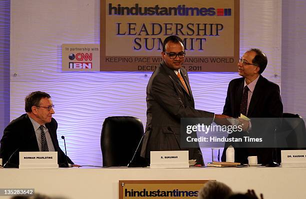 Kaushik Basu shakes hand with R. Sukumar as Norman Pearlstine chief content officer of Bloomberg L.P looks on during the first day of the Hindustan...