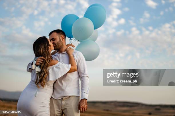 husband and wife in love revealing baby gender in nature - gender reveal stock pictures, royalty-free photos & images