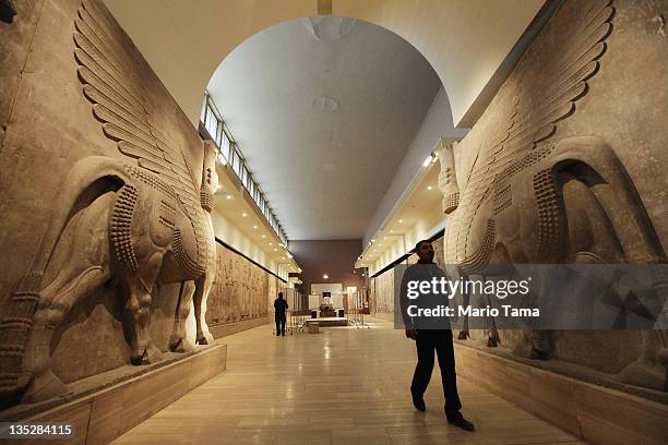 Worker walks past sculptures of human-headed bulls in the renovated Assyrian room at Iraq's National Museum on December 8, 2011 in Baghdad, Iraq. The...