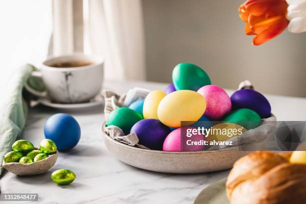 colorful easter eggs with cup of coffee on table - paasontbijt stockfoto's en -beelden