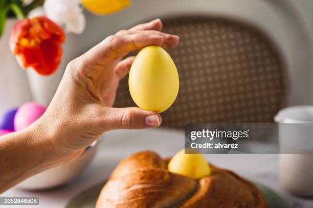 hand einer frau mit gelb gefärbtem osterei - easter egg stock-fotos und bilder