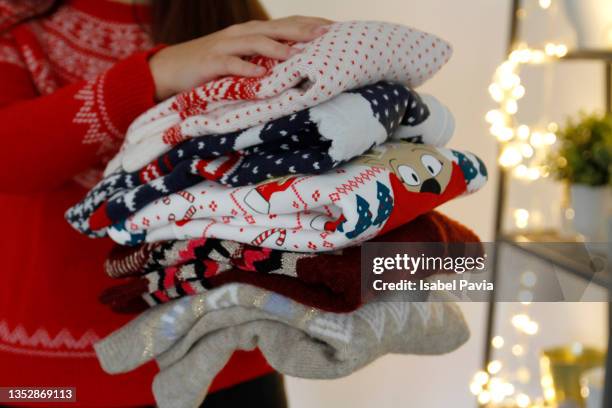 woman holding stack of folded christmas sweaters - christmas jumper 個照片及圖片檔