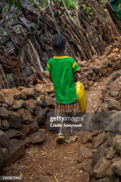 afrikanisches mädchen, das wasser aus dem brunnen trägt, äthiopien, afrika - traditional ethiopian girls stock-fotos und bilder