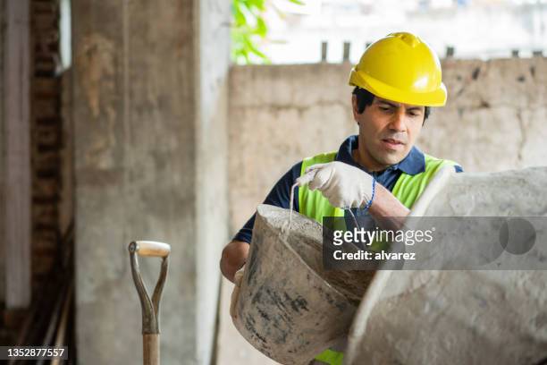 trabajador de la construcción agregando cemento en la hormigonera en un sitio de construcción - folding fotografías e imágenes de stock